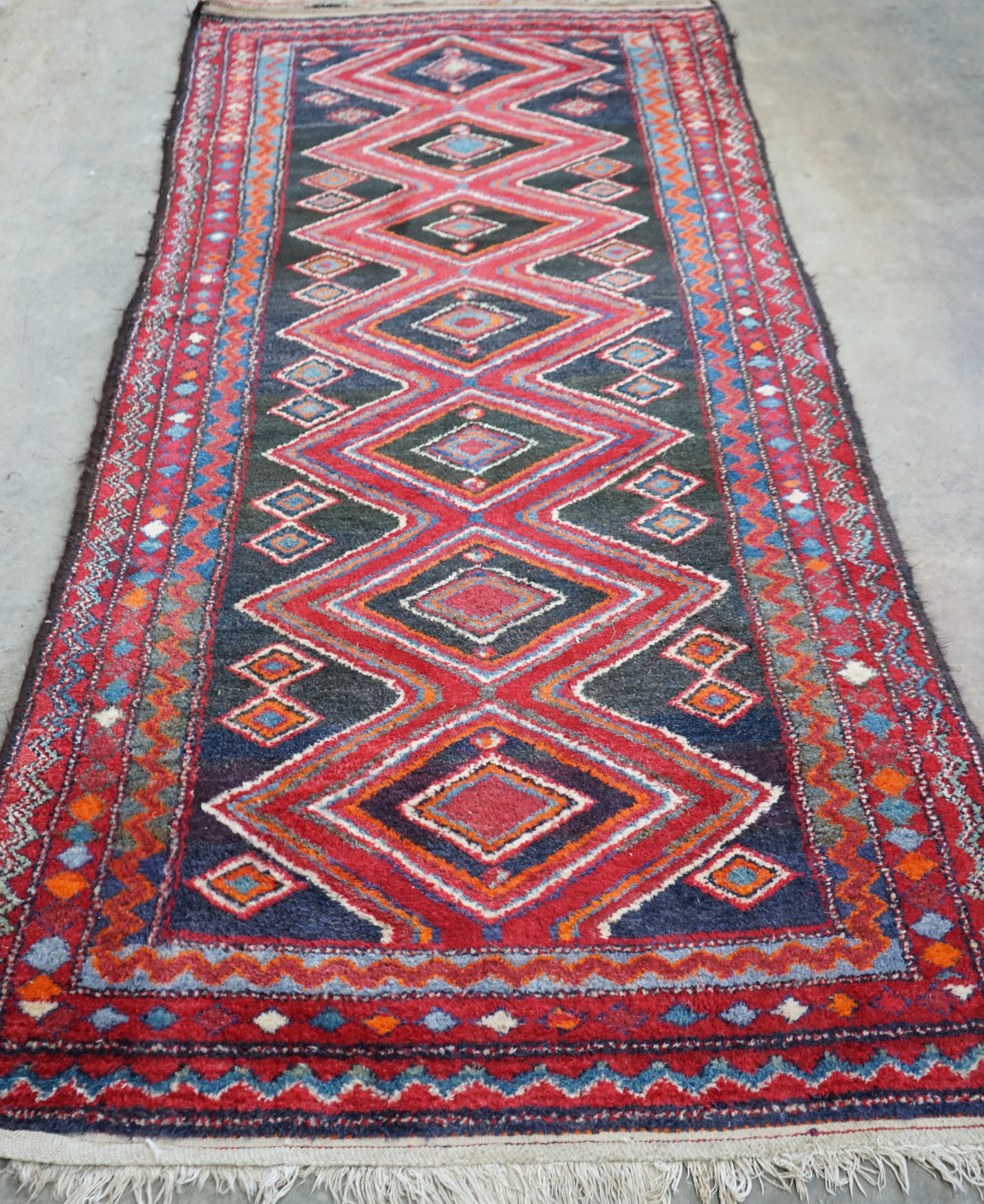 A Belouch blue and red ground rug, 256 x 116cm